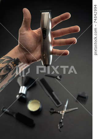 Hand of male barber with equipment set isolated on black table background. Hand of male barber with equipment set isolated on black table background. 74842994