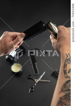 Hand of male barber with equipment set isolated on black table background. Hand of male barber with equipment set isolated on black table background. 74842996