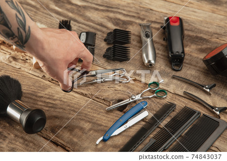 Hand of male barber with equipment set isolated on wooden table background. 74843037