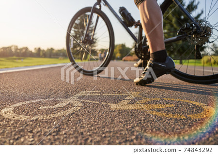 Close up of a bicycle sign drawn on asphalt. Professional male cyclist standing with his road bike on a cycle path 74843292