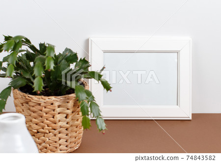 Front view of white poster frame mockup with plant in a pot Front view of white poster frame mockup with plant in a pot 74843582