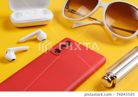Smartphone, wireless earphones, sunglasses and lipstick 74843585