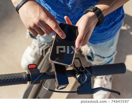 Young man using smartphone to unlock a shared electric scooter Young man using smartphone to unlock a shared electric scooter 74843597