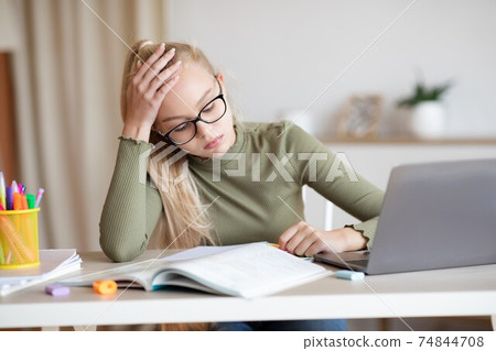 Teenager blonde girl having difficulties with studying, home interior 74844708