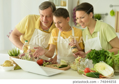 Portrait of cute family cooking together in kitchen Portrait of cute family cooking together in kitchen 74844858
