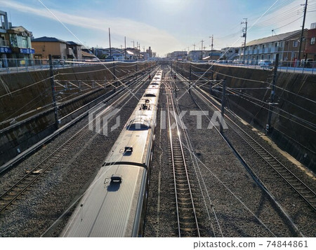 Musashino Line train running away from Higashi-Tokorozawa toward the sun 74844861