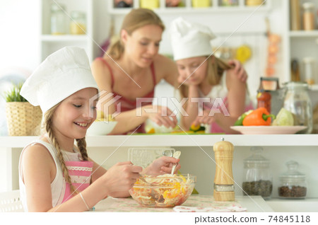 Portrait of cute girl eating salad on kitchen Portrait of cute girl eating salad on kitchen 74845118