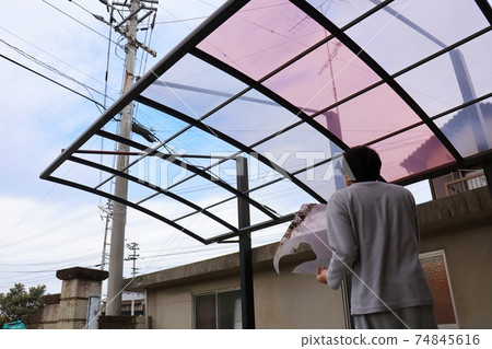 A man staring at a carport broken by a strong wind (with permission from the landowner) 74845616
