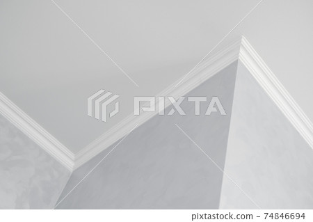 White ceiling with a white plinth in a room with gray painted walls. Decoration of the corner between the ceiling and the wall in the room. Ceiling molding in the interior. Detail of corner. White ceiling with a white plinth in a room with gray painted walls. Decoration of the corner between the ceiling and the wall in the room. Ceiling molding in the interior. Detail of corner. 74846694