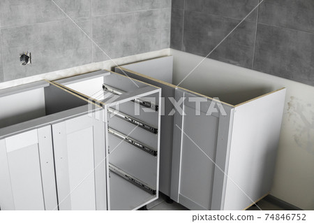 Lower custom kitchen cabinets installation with a furniture facades mdf. Gray modular kitchen from chipboard material on a various stages of installation. A frame furniture fronts mdf profile. 74846752