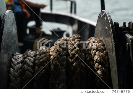 Rope on a sea boat for mooring a vessel is adhered to a pier. 74846776