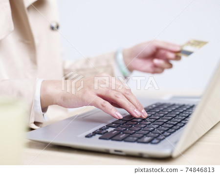hands of a young asian woman entering credit card numbers using laptop computer hands of a young asian woman entering credit card numbers using laptop computer 74846813
