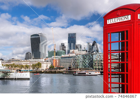 London with modern city against red phone booth with boats on Thames river in England, UK London with modern city against red phone booth with boats on Thames river in England, UK 74846867