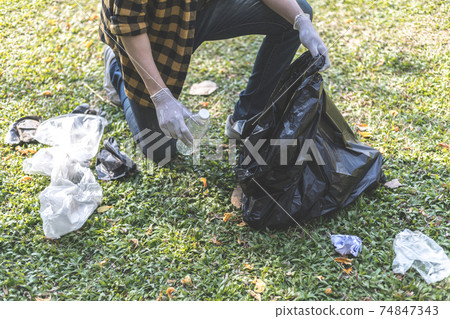 Male volunteers carry water bottles or plastic bags that have fallen in the park put them in trash cans, Environmental protection or volunteering for charity, Waste disposal through recycling. Male volunteers carry water bottles or plastic bags that have fallen in the park put them in trash cans, Environmental protection or volunteering for charity, Waste disposal through recycling. 74847343