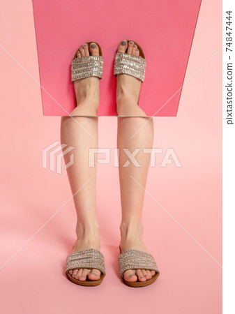 Female fit legs in fashionable shoes on coral pink background with mirror. Style and beauty concept. Close up. 74847444