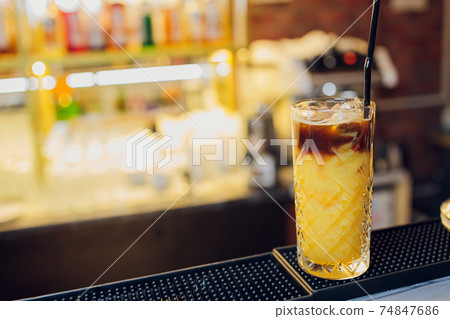 beautiful frozen cocktail glass with ice, mint and pineapple on a dark wooden bar counter, bokeh bright background. beautiful frozen cocktail glass with ice, mint and pineapple on a dark wooden bar counter, bokeh bright background. 74847686
