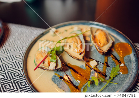Large plate with mussels cooked in tomato sauce with garlic, parsley and lemon. Free space for your text. Large plate with mussels cooked in tomato sauce with garlic, parsley and lemon. Free space for your text. 74847781