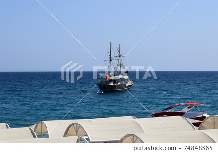 Large sailing ship in the Mediterranean sea in a pirate style in the open sea against a blue sky. Large sailing ship in the Mediterranean sea in a pirate style in the open sea against a blue sky. 74848365