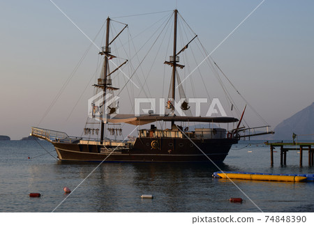 Large sailing ship in the Mediterranean sea in a pirate style in the open sea against a blue sky. Large sailing ship in the Mediterranean sea in a pirate style in the open sea against a blue sky. 74848390