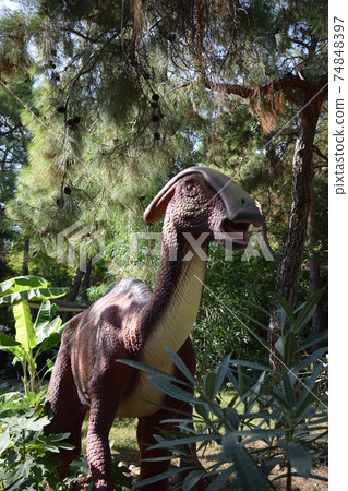 Dinosaur statue in the forest park in nature for background. Realistic sculpture of a dinosaur Parasaurolophus full-size in the DinoPark 74848397