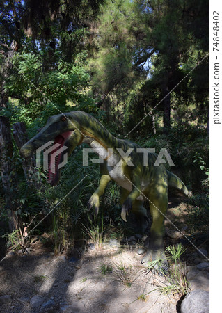 Roaring Baryonyx standing in tall grass display model Dinosaur statue in the forest park in nature for background. 74848402