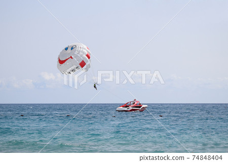 Funny parasail wing pulled by a boat. Sea summer recreation. Summer water beach extreme sports. 74848404