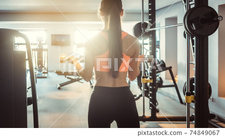 Young woman lifting weights in her private gym 74849067