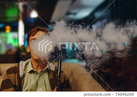 Man in restaurant smoking hookah. Man in restaurant smoking hookah. 74849209