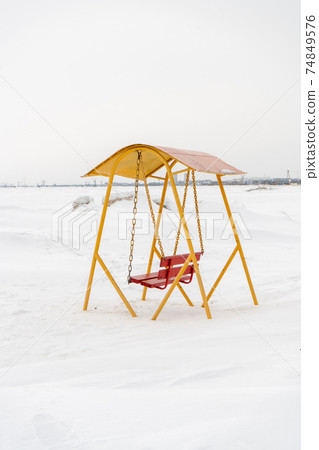 An old swing against the background of a snowy shore. An old swing against the background of a snowy shore. 74849576