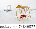 An old swing against the background of a snowy shore. 74849577