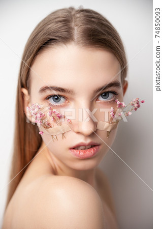 Young woman with flowers on face on white background Young woman with flowers on face on white background 74850093