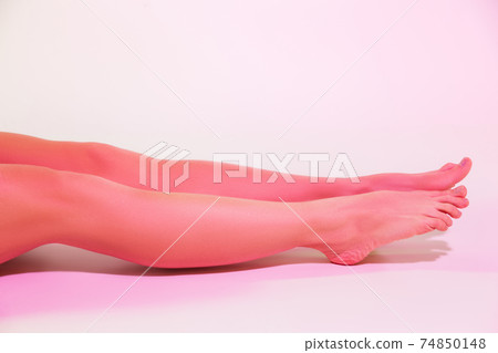 Barefoot slim woman sitting on floor in white studio Barefoot slim woman sitting on floor in white studio 74850148