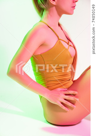 Tired female gymnast sitting on floor in studio Tired female gymnast sitting on floor in studio 74850149
