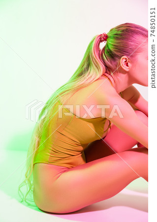Tired female gymnast sitting on floor in studio Tired female gymnast sitting on floor in studio 74850151