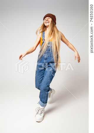 Energetic hipster woman in trendy wear dancing in studio Energetic hipster woman in trendy wear dancing in studio 74850160