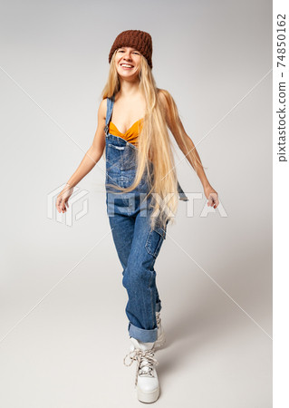 Energetic hipster woman in trendy wear dancing in studio Energetic hipster woman in trendy wear dancing in studio 74850162