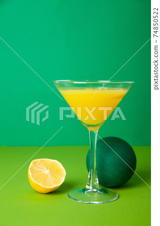 Refreshing drink in cocktail glass placed on table near lemon 74850522