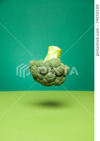 Tasty fresh broccoli head levitating in green studio 74850589