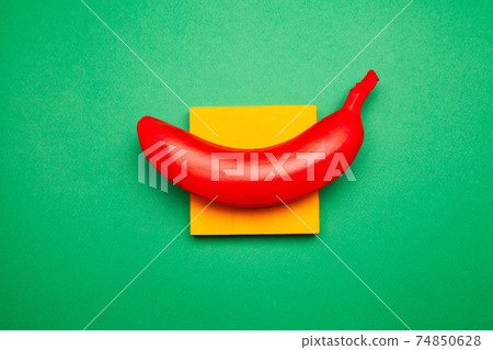 Bright composition of red banana and yellow sticky notes on green surface 74850628
