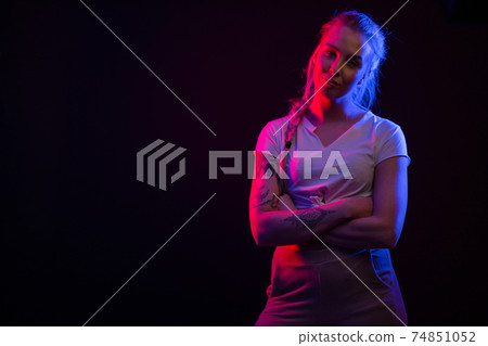 Colorful portrait of a confident blonde woman wearing white top on black backgound 74851052