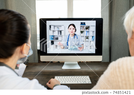 Patient and general practitioner looking at computer with doctor on screen Patient and general practitioner looking at computer with doctor on screen 74851421