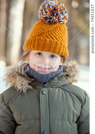 Adorable child in warm jacket and knitted brown beanie looking at you outside 74851837