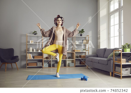 Happy calm young woman enjoying yoga practice and doing Tree pose with eyes closed 74852342