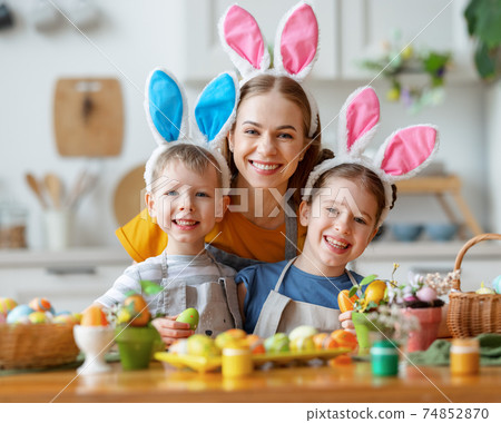 Happy easter! family mother and cheerful children with ears hare getting ready for holiday Happy easter! family mother and cheerful children with ears hare getting ready for holiday 74852870