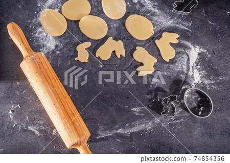 Rolling pin and kitchenware for making easter cookies on dark background 74854356