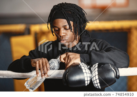 African male boxer in black gloves at the gym 74854910