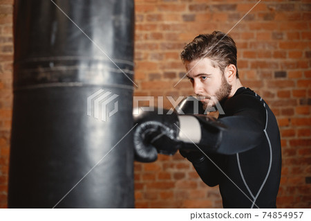 Male boxer in black gloves at the gym Male boxer in black gloves at the gym 74854957