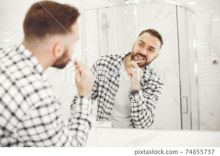 Portrait view of a young man brushing his teeth Portrait view of a young man brushing his teeth 74855737