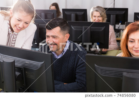 Serious businesswoman helping to man, pointing at computer monitor Serious businesswoman helping to man, pointing at computer monitor 74856080