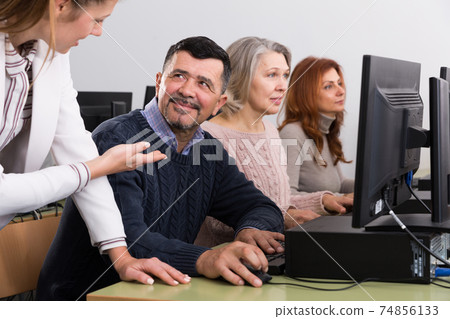 Businesswoman helping to coworkers, pointing at computer monitor Businesswoman helping to coworkers, pointing at computer monitor 74856133